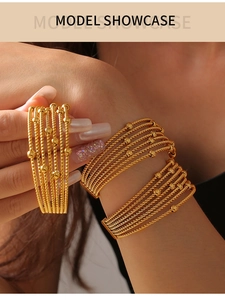 Detail of multi-layered gold titanium steel bracelet with twisted rope and bead patterns