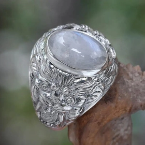 Detailed macro of vintage dragon head ring with moonstone on rustic wood base