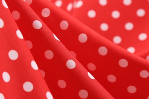 Macro shot of red fabric with white polka dots showing smooth texture and soft folds