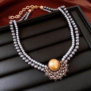 Détail du collier double rang en perles grises avec pendentif pétale doré sur soie