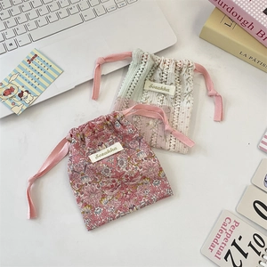 Détail de pochettes à cordon en tissu floral et dentelle pour produits de beauté