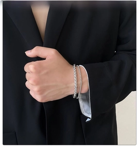 Close-up of a men's double-layer silver stainless steel chain bracelet on a wrist