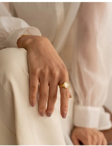 Macro view of a gold-plated ring featuring an oval white mother-of-pearl gemstone