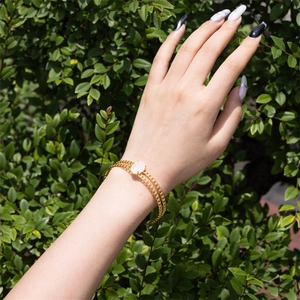 Detail of a vintage gold bracelet with pink oval natural stone worn on a female wrist