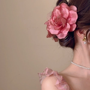 Detail of pink fabric flower hair clip worn by model with matching pearl accessories