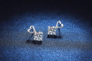 Macro shot of S925 silver heart stud earrings with round moissanite on dark background
