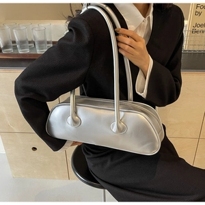 Chic silver underarm bag shown on a model in a black suit for an elegant office look
