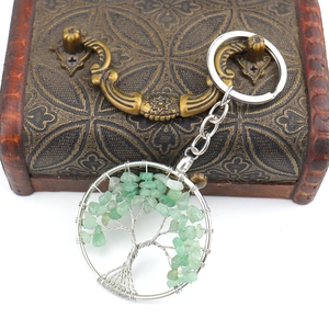 Detail of tree of life keychain with green natural crushed stones on vintage wood box
