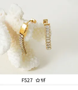 Close-up of gold hoop earrings featuring rectangular clear zircons on coral decor