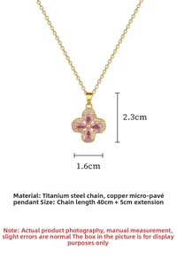 Macro detail of gold-plated clover necklace pendant with pink zircons and size markings