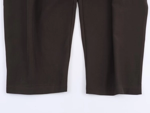 Detail of dark brown trousers showing flat hemline and high-quality stitching work
