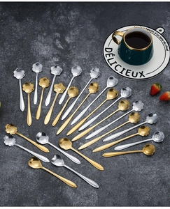 Flat lay of gold and silver flower shaped stainless steel spoons on a stone table