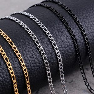 Three Figaro chains in gold, silver, and black finish displayed on a black leather stand