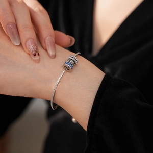 Detailed macro view of S925 silver bracelet with blue zircon LOVE charm on wrist