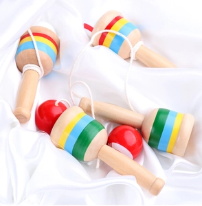 Detailed view of colorful striped wooden cup and ball game toys on white silk fabric