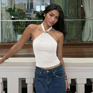 Close-up of a white halter neck top featuring a decorative golden metal buckle detail