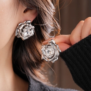 Vue macro de boucles d'oreilles rose argentée avec cristal carré sur l'oreille et la main
