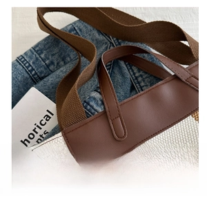 Detail of striped canvas tote bag with brown leather trim and dual strap design