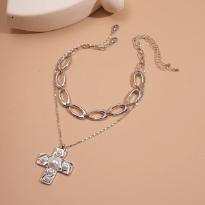 Détail du collier double couche argenté avec maillons et pendentif croix en perle