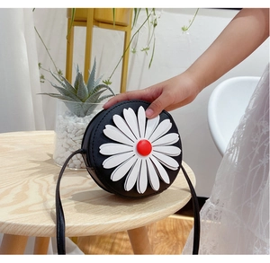 Detail of a mini round crossbody bag for girls featuring a white daisy on black PU leather