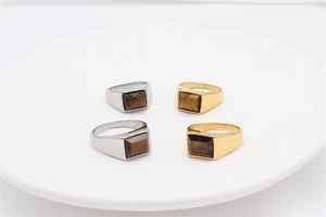 Macro shot of silver and gold signet rings with rectangular tiger eye stones on white stand
