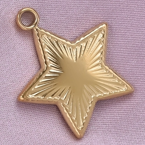 Macro shot of gold star pendant with radial engraving on soft purple silk fabric