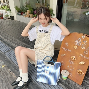 Blue and white striped canvas tote bag held by a model in a casual outdoor setting