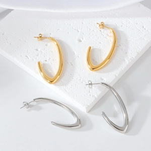 Minimalist irregular C-shaped gold and silver earrings on white stone tray and silk