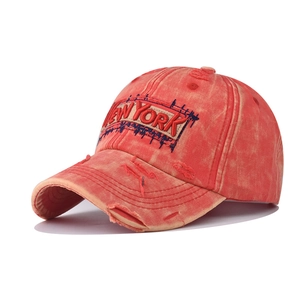 Macro detail of vintage washed orange baseball cap with New York embroidery and distressed holes