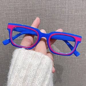 Dettaglio di montatura quadrata bicolore rosa e blu tenuta in mano dallo stile vintage