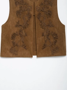 Detail of floral embroidery on brown suede vest featuring sleeveless open-front design