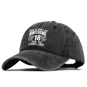 Detail of embroidered '18 Years Old' text on black washed cotton baseball cap texture