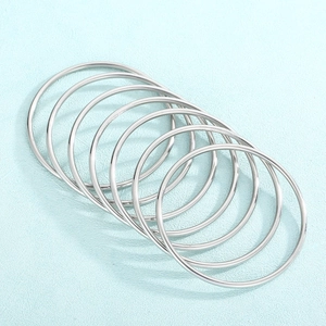 Close-up of seven-piece polished 3mm silver stacked bangles on light blue leather