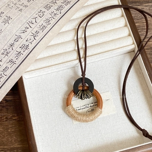 Detail of wooden rings with hemp rope wrap and bronze hardware on brown suede cord