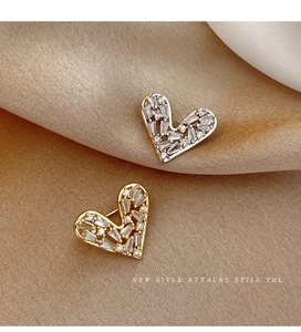 Detail of gold and silver heart brooches with micro-pave crystals on champagne silk