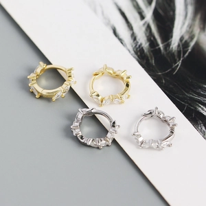 Detailed close-up of gold and silver ear hoops set with marquise-cut zircons