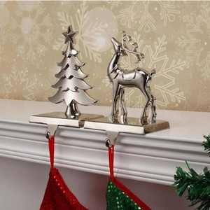 Close-up of silver metal Christmas stocking holders in reindeer and tree shapes on a mantel
