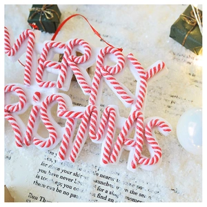 Close-up of Merry Christmas letter sign with red and white candy cane stripes on snow