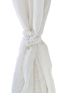 Close-up of handmade bohemian cotton rope curtain tieback with woven texture