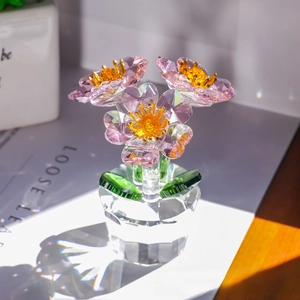 Detail of three-headed pink crystal flowers with green leaves on faceted glass base