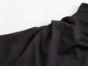 Detail of black nylon asymmetric dress showing fabric texture and high-quality stitching