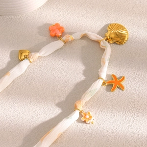 18K gold plated necklace with silk ribbon and gold shell charms on beige background
