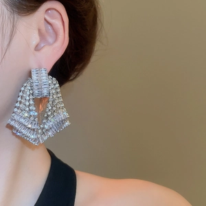 Close-up of sparkling silver tassel earrings with crystals on a female model