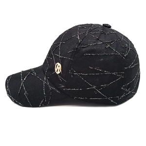 Close-up of black baseball cap featuring irregular silver stitching and metallic side logo