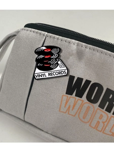Detailed close-up of retro vinyl record enamel pins attached to a grey canvas bag