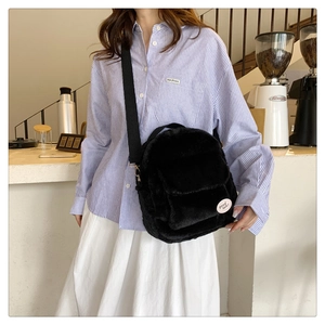 Vista lateral de mujer con bolso bandolera de felpa negra y correa ajustable con insignia