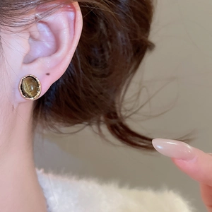 Close-up of vintage geometric tiger eye stud earrings in gold worn by a model