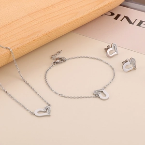 Dettaglio del set di gioielli a cuore in argento con collana e orecchini su vassoio in legno