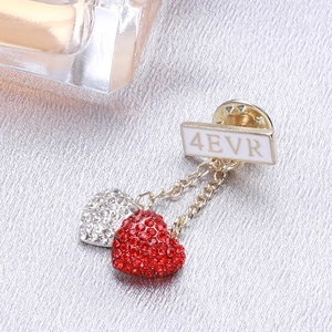 Macro view of golden 4EVR brooch with dangling red and silver rhinestone heart charms