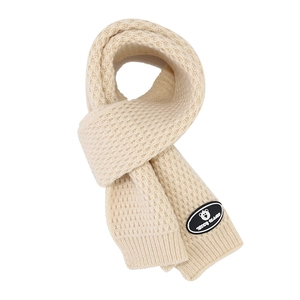 Detailed view of beige chunky knit scarf with honeycomb texture and Teddy Island patch
